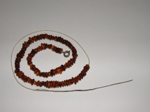 Re-stringing my amber bead necklace using linen yarn and a boar's bristle needle.