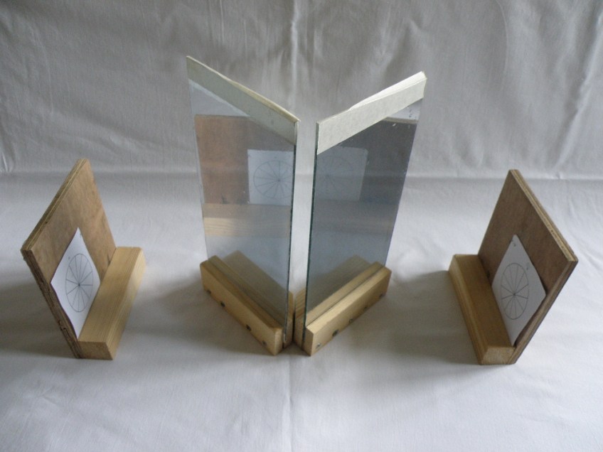 The image plates, pair of images and mirrors of the Deville plotter. Deville instructed the mirroring to be "light". The mirrors have only a thin layer of silvering. this means that the mirrors are reflective, but they also let some light through. This means that you see the reflected drawings; but that the plotter's pin-prick of light shines through from behind.